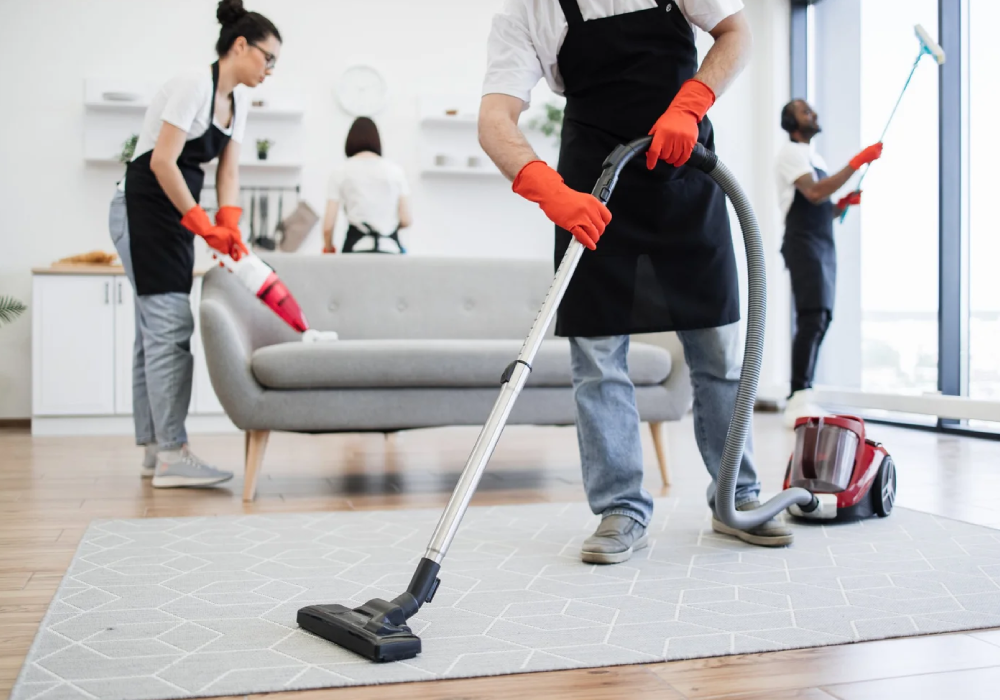 professional house cleaning team vacuuming and sanitizing a living room